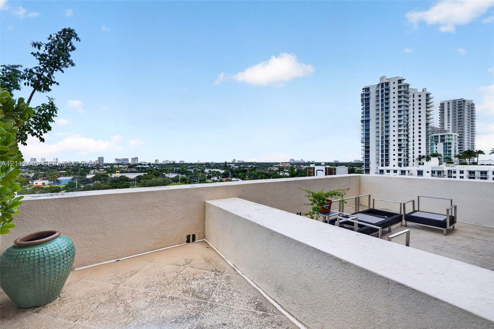 Spacious outdoor terrace off the primary bedroom featuring a concrete floor, stone-texture finish, and wide perimeter parapet walls