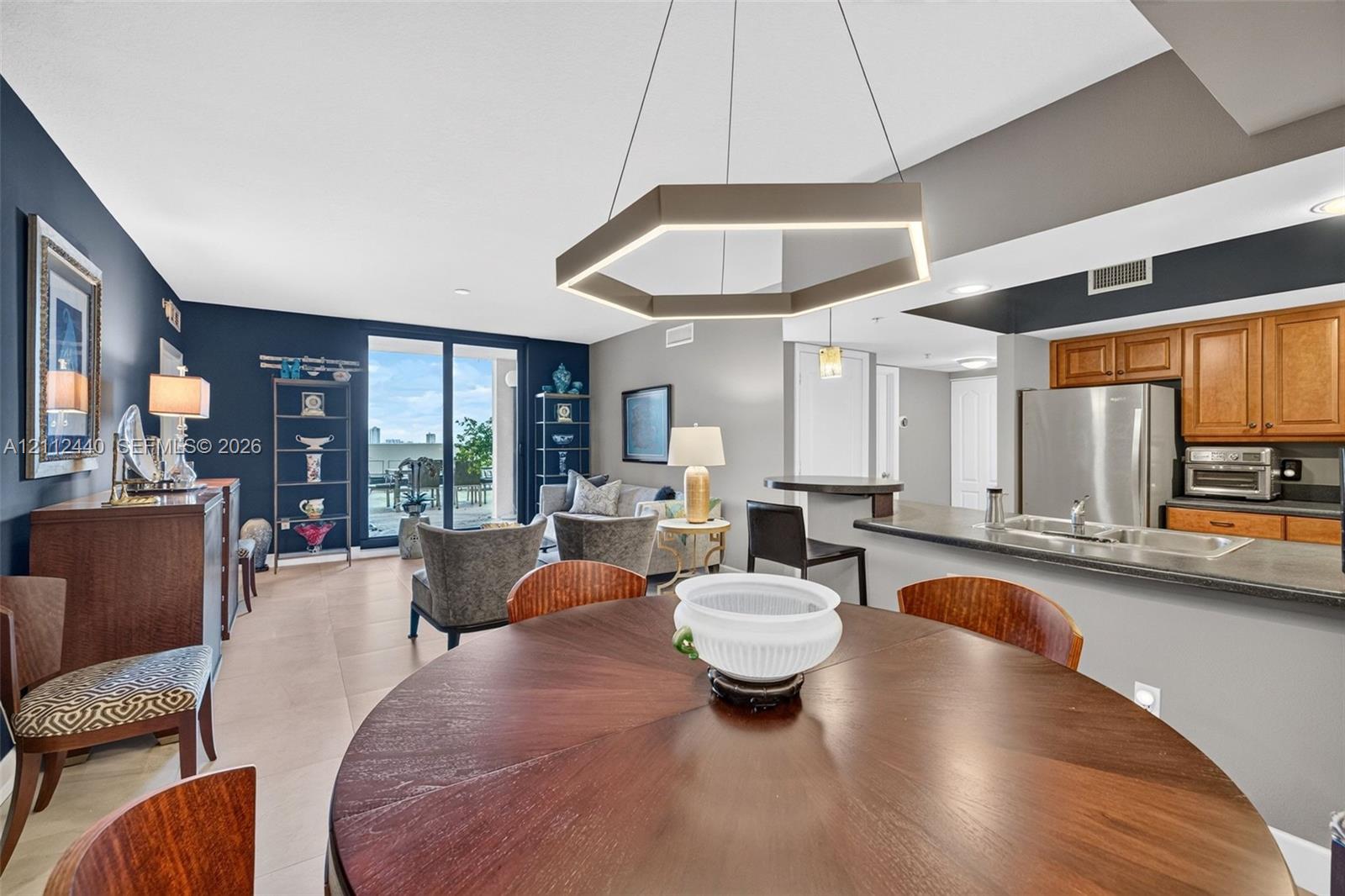 Open-concept area featuring porcelain flooring, kitchen breakfast bar - upgraded wooden cabinetry, and sliding glass doors to the huge terrace (chandelier does not convey)