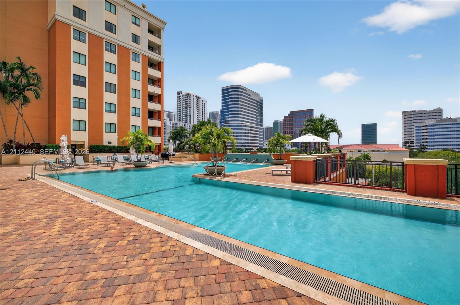 Swimming pool featuring a stone-paver deck, integrated water features, and perimeter metal fencing