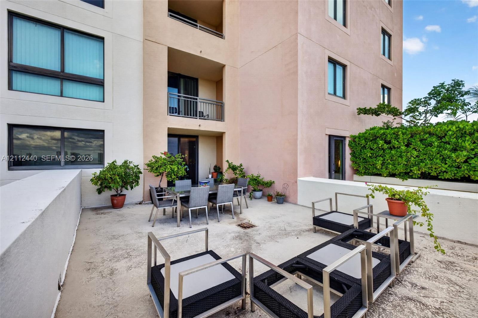 Expansive outdoor terrace featuring concrete flooring, a covered recessed area, and low-profile concrete perimeter walls