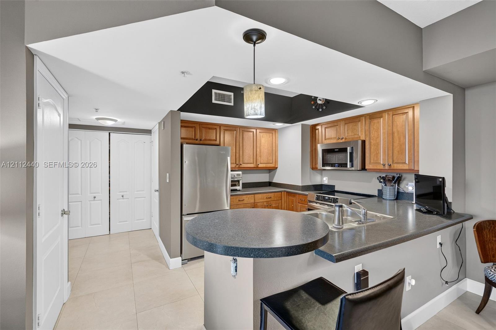 Kitchen featuring wood cabinets, stainless appliances, a breakfast bar, and porcelain flooring