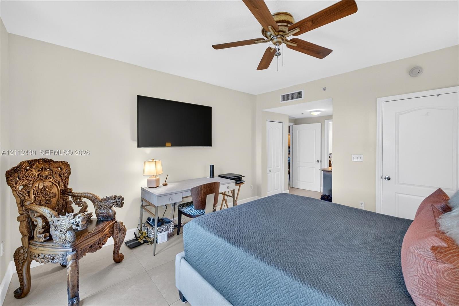 Neutral-toned interior featuring large-format porcelain flooring, a ceiling fan with wood-finish blades, and a walk in closet as well as separate coat closet