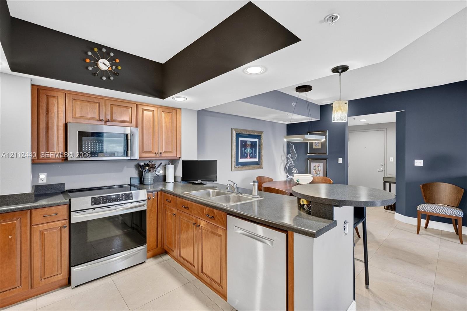 Kitchen featuring upgraded wood cabinetry, stainless appliances, dark countertops, a built-in peninsula, and recessed lighting