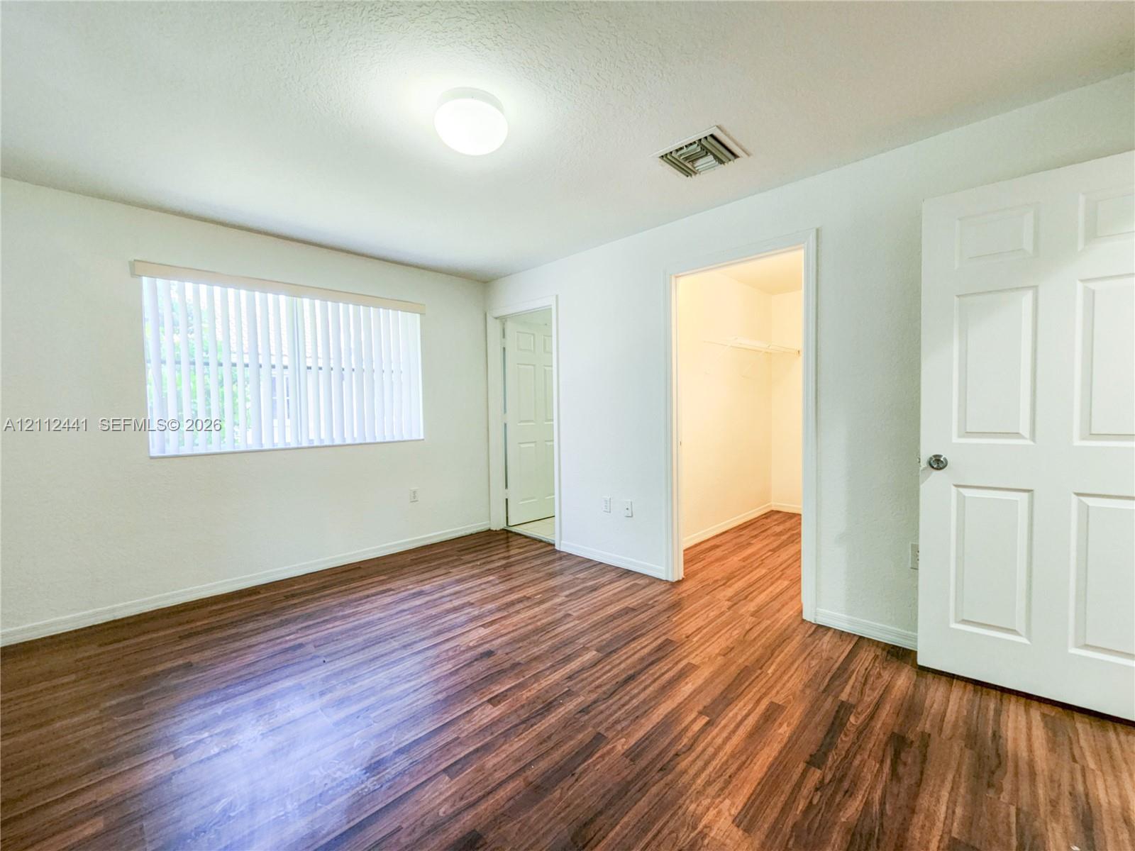 Wood-finish flooring, vertical window blinds, and interior six-panel doors