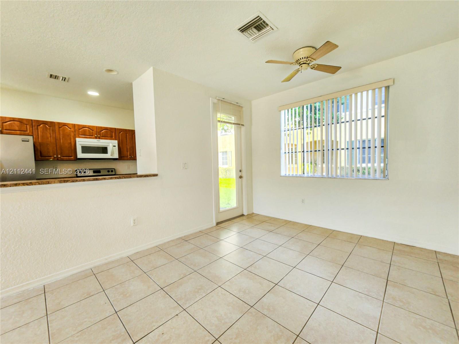 Kitchen area featuring wood cabinetry, stone-finish countertops, stainless steel appliances, neutral tile flooring, and a ceiling fan Kitchen area featuring wood cabinetry, stone-finish countertops, stainless steel appliances, neutral tile flooring, and a ceiling fan