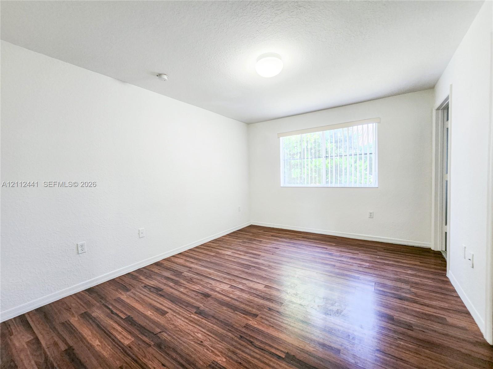 Interior space featuring wood-finish flooring, white walls, and a recessed ceiling light fixture Interior space featuring wood-finish flooring, white walls, and a recessed ceiling light fixture