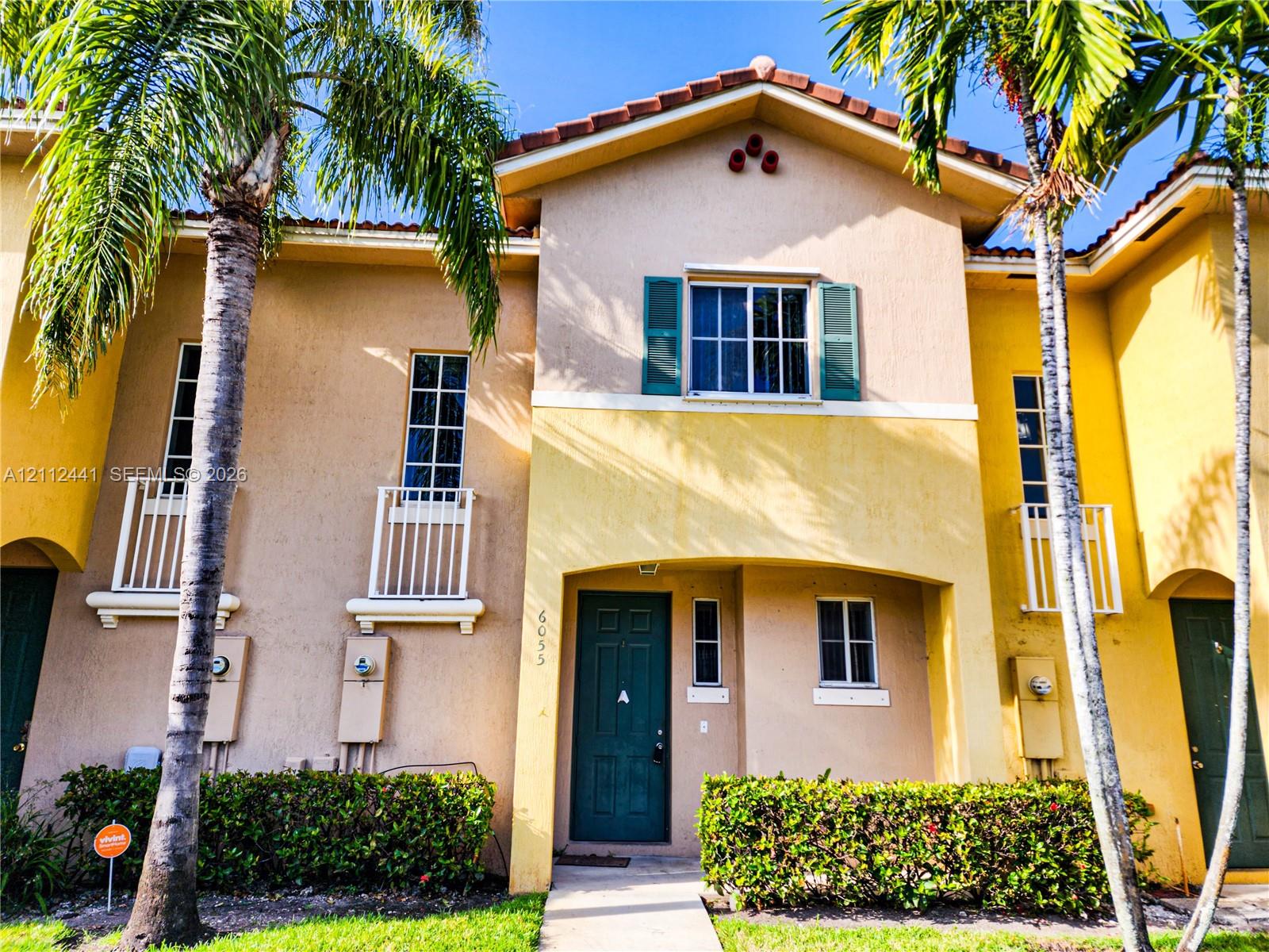 Stucco exterior featuring dual-tone paint, decorative window shutters, metal balcony railings, and a tile roof Stucco exterior featuring dual-tone paint, decorative window shutters, metal balcony railings, and a tile roof