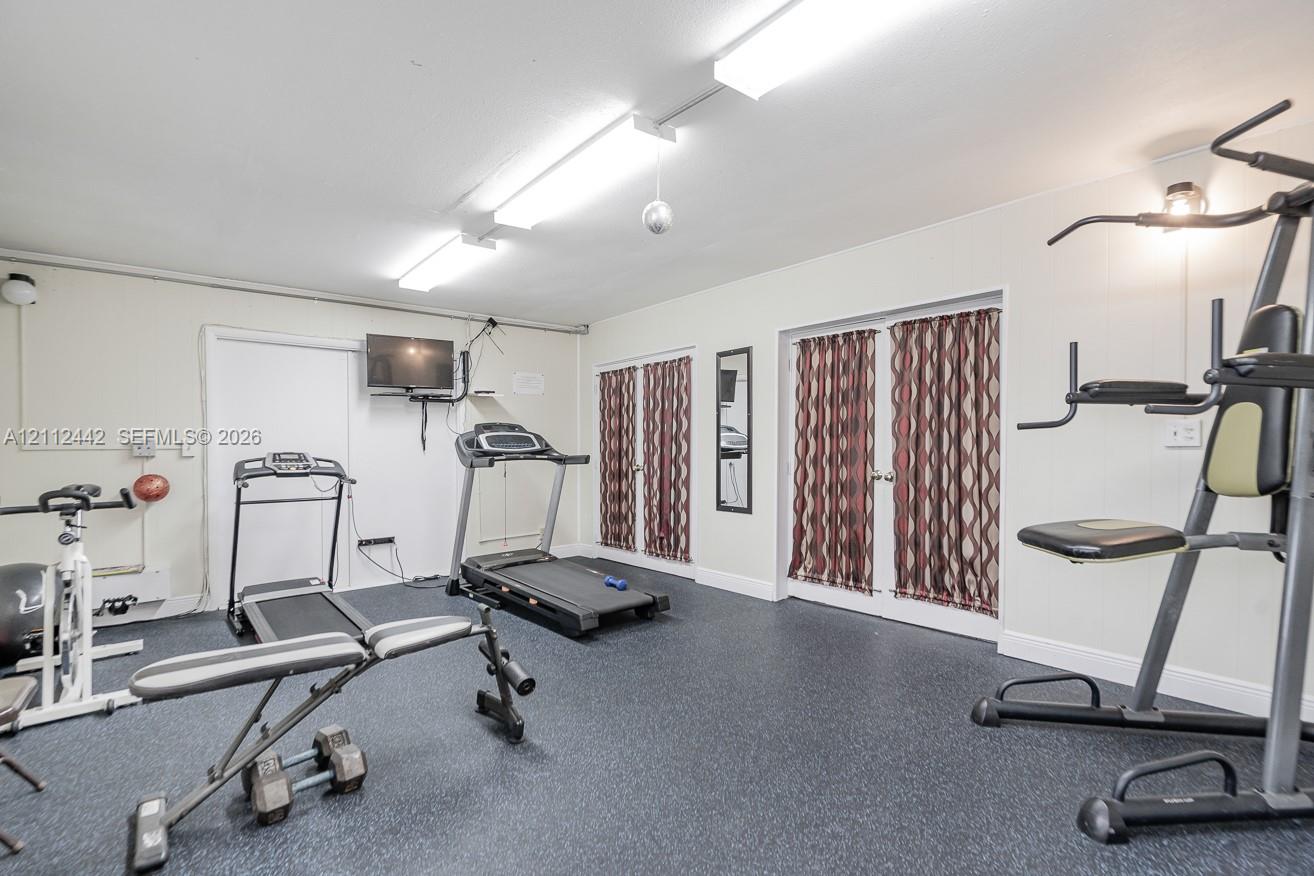 Interior room featuring dark rubber flooring, white walls, and dual sets of glass-paneled doors with metallic hardware