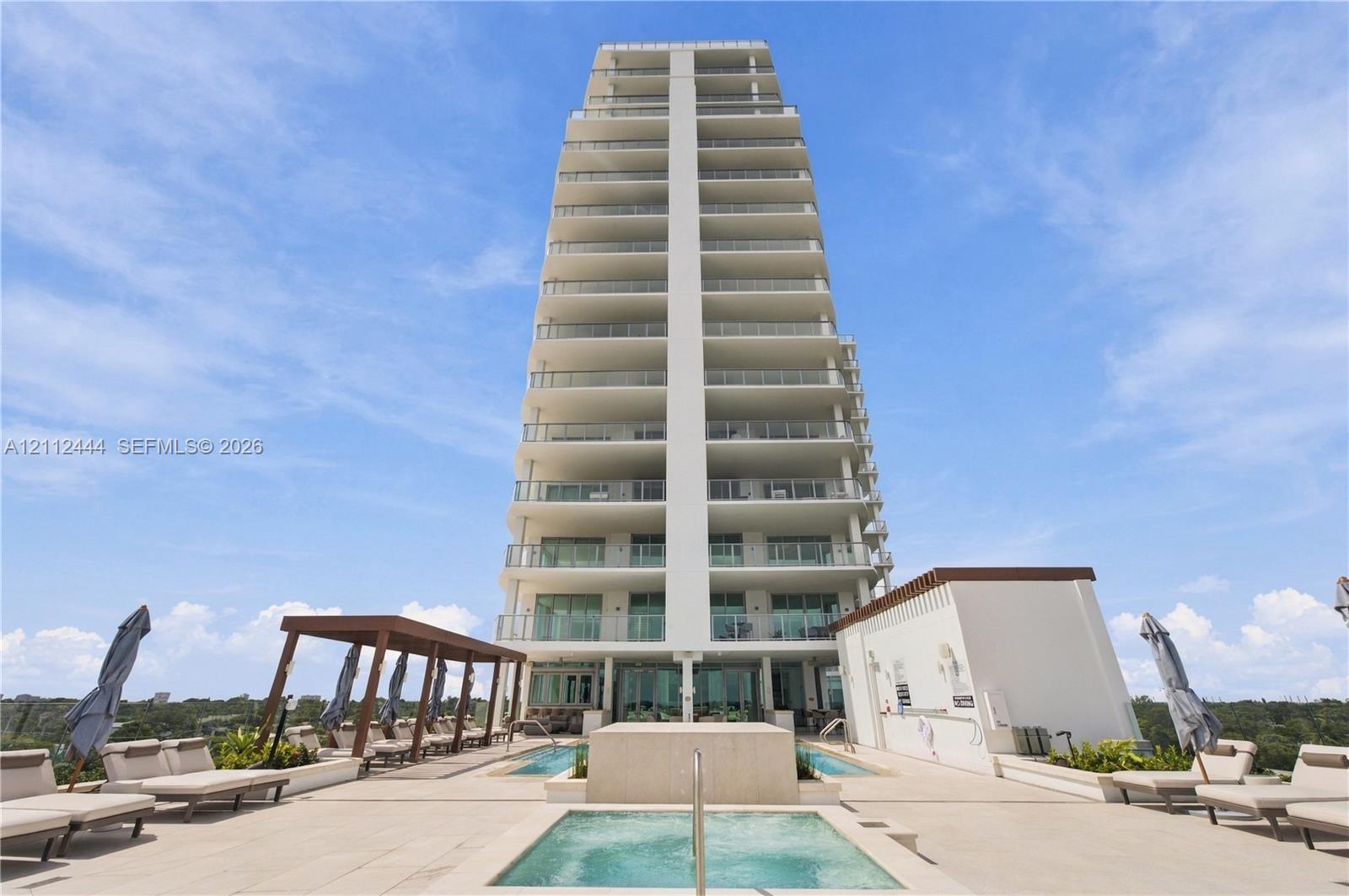 High-rise building exterior featuring tiered balconies with metal railings, elevated terrace level, tiled sundeck, built-in swimming pool, and custom pergola structure
