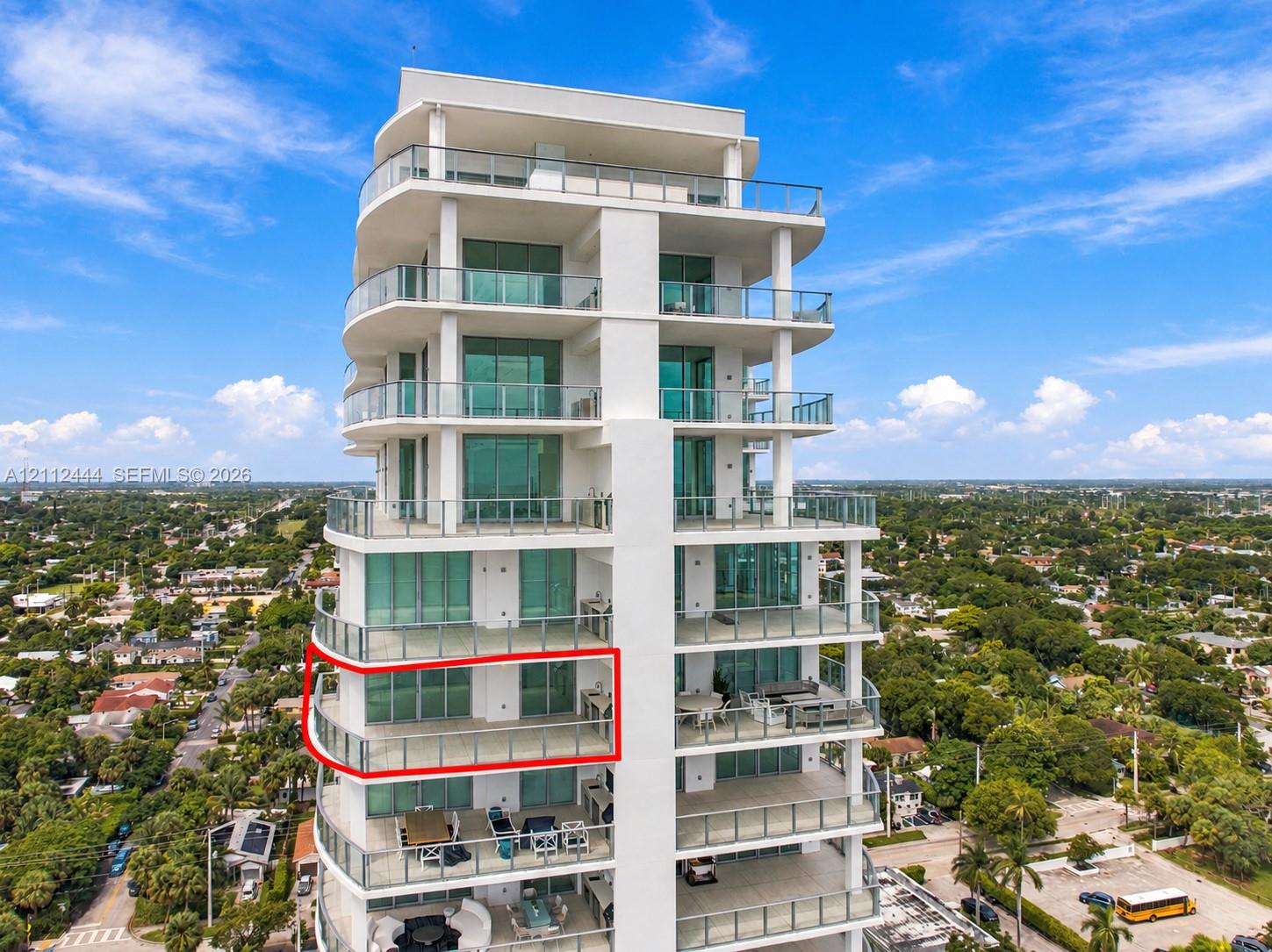 High-rise residential exterior featuring glass-railed private balconies, floor-to-ceiling windows, and integrated outdoor kitchen fixtures