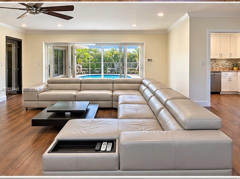 Open-concept living space featuring wood-finish flooring, recessed lighting, ceiling fan, and multi-panel sliding glass doors providing access to an enclosed pool area Open-concept living space featuring wood-finish flooring, recessed lighting, ceiling fan, and multi-panel sliding glass doors providing access to an enclosed pool area