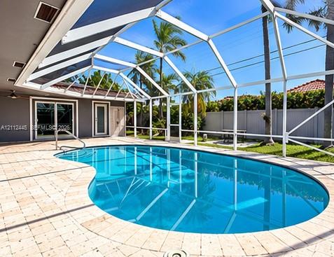 Screen-enclosed swimming pool with a concrete paver deck, metal pool cage, and privacy fencing Screen-enclosed swimming pool with a concrete paver deck, metal pool cage, and privacy fencing