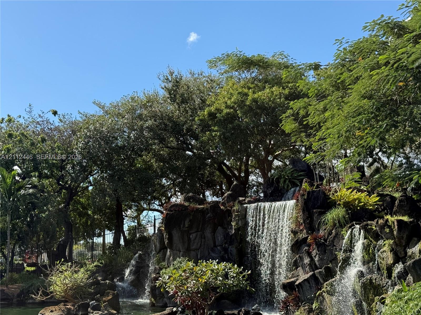 Multi-tiered stone waterfall feature with mature landscaping and established trees