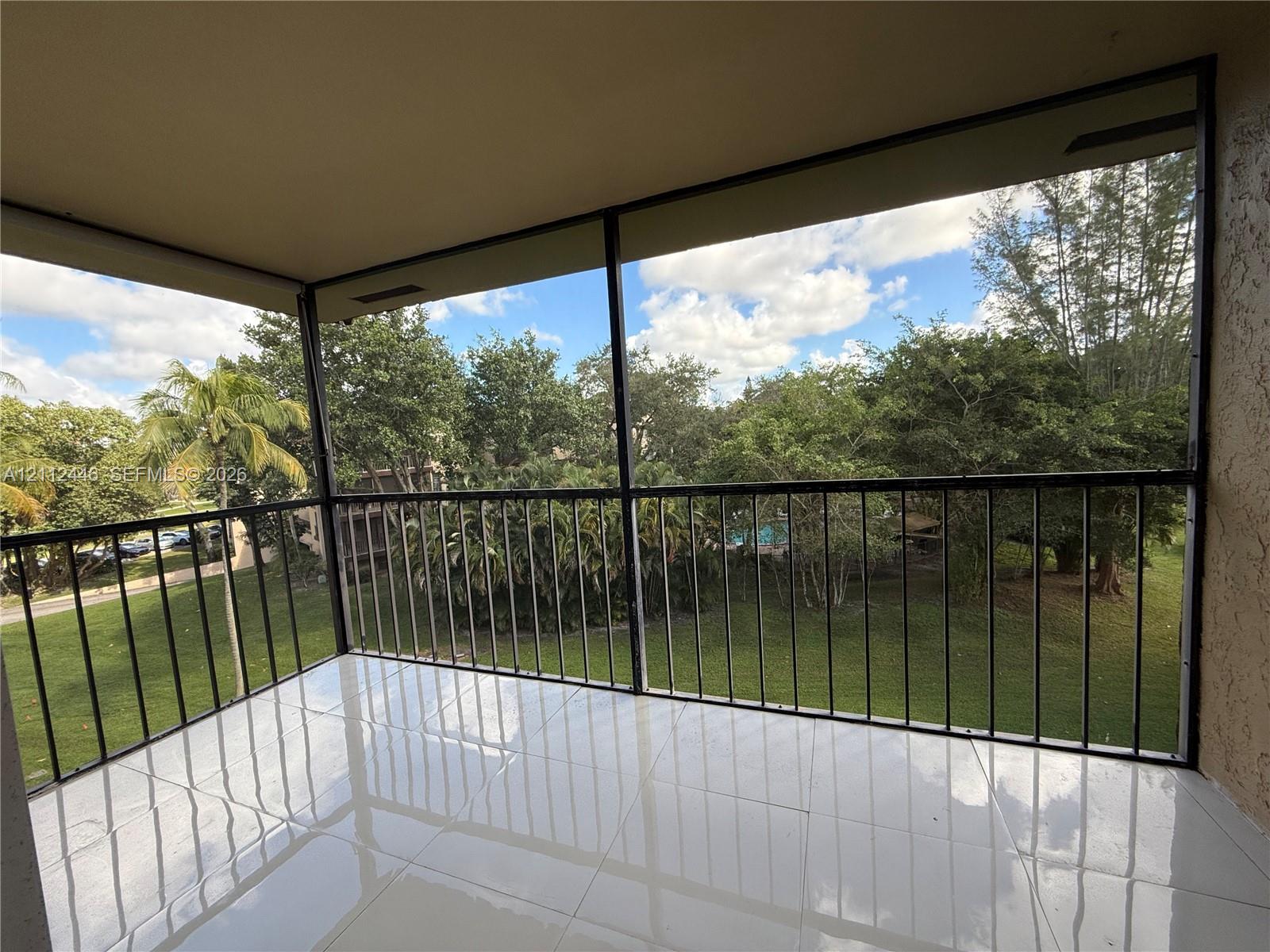 Screened-in balcony featuring white tile flooring, black metal railing, and a textured stucco ceiling Screened-in balcony featuring white tile flooring, black metal railing, and a textured stucco ceiling