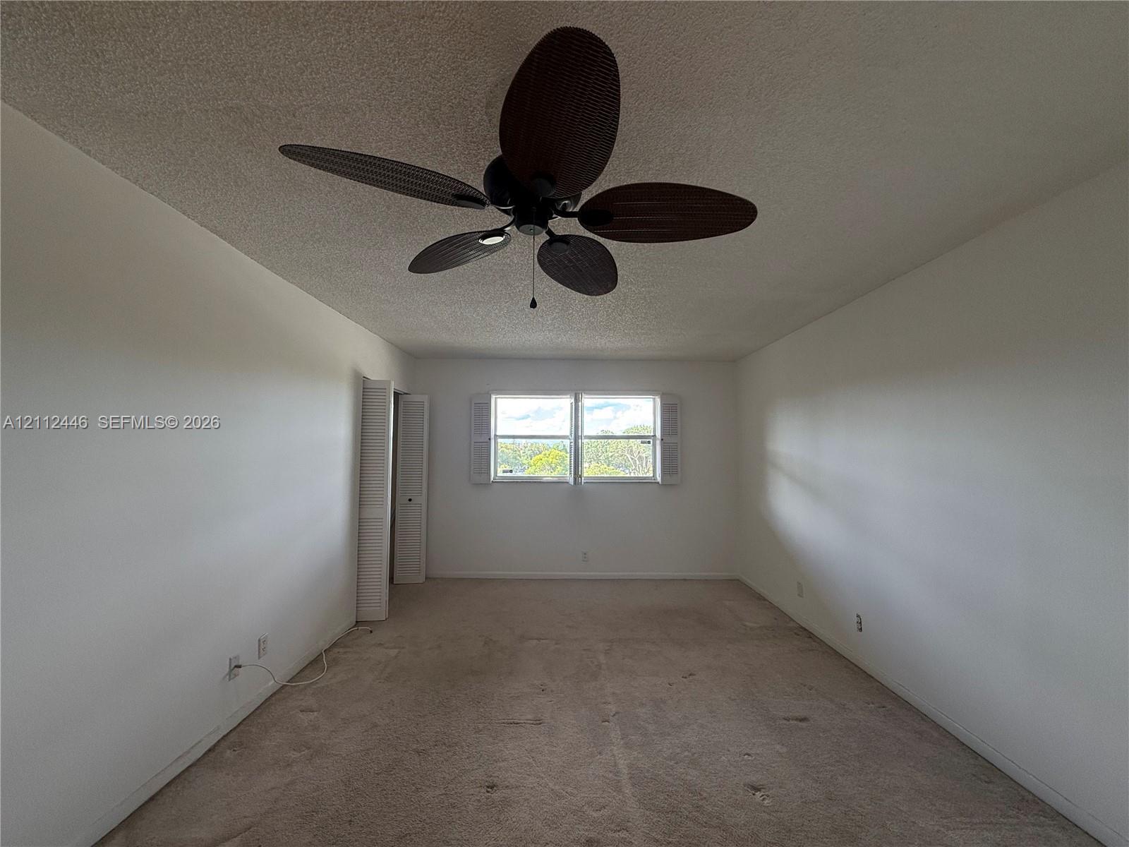 Room featuring a multi-blade ceiling fan, wall-to-wall carpeting, and double-hung windows with white shutters