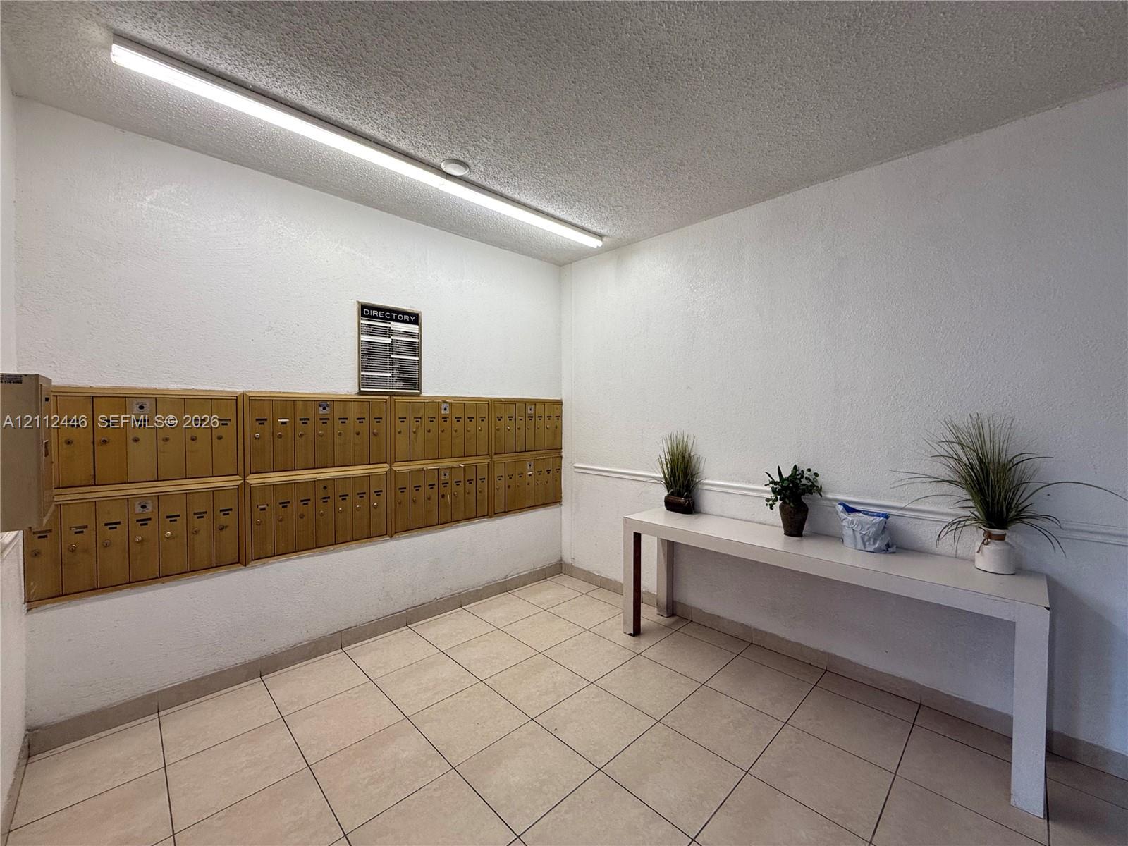 Wall-mounted metal mailboxes, linear ceiling-mounted lighting, and tile flooring