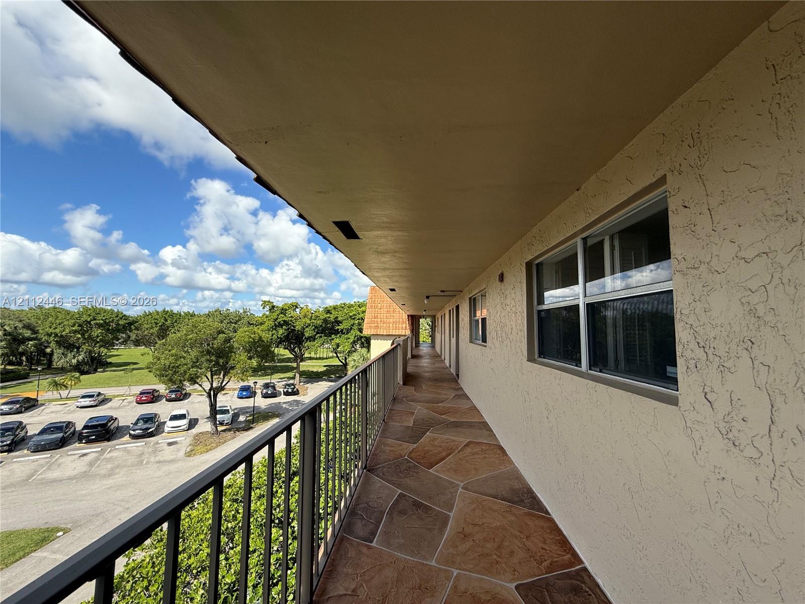 Exterior walkway featuring flagstone-style flooring, a metal railing, and stucco wall finishes