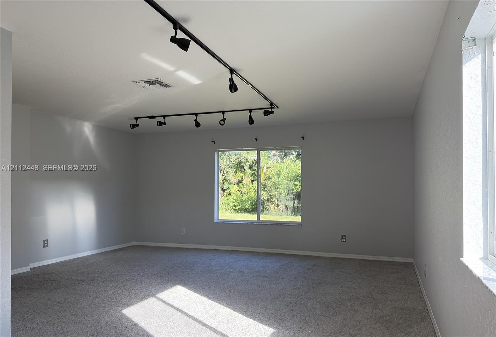 Interior space featuring wall-to-wall carpeting, neutral-toned walls, and black industrial-style track lighting