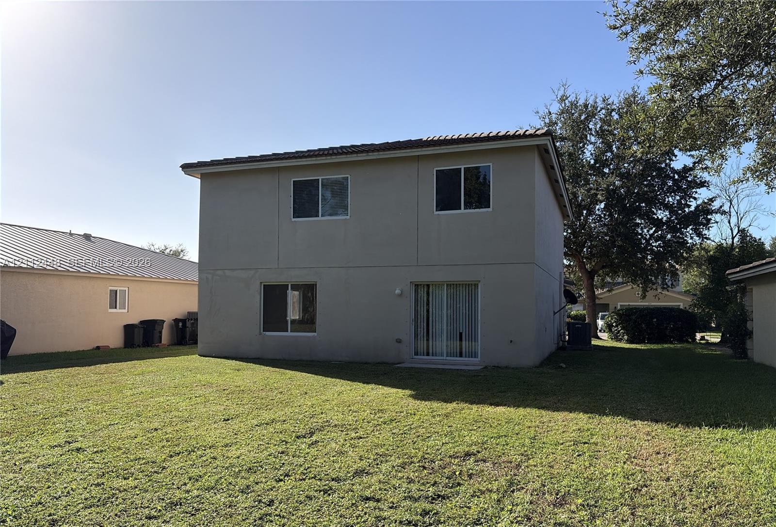 Two-story exterior featuring a neutral stucco finish, a hip roof with tile shingles, and sliding glass patio doors