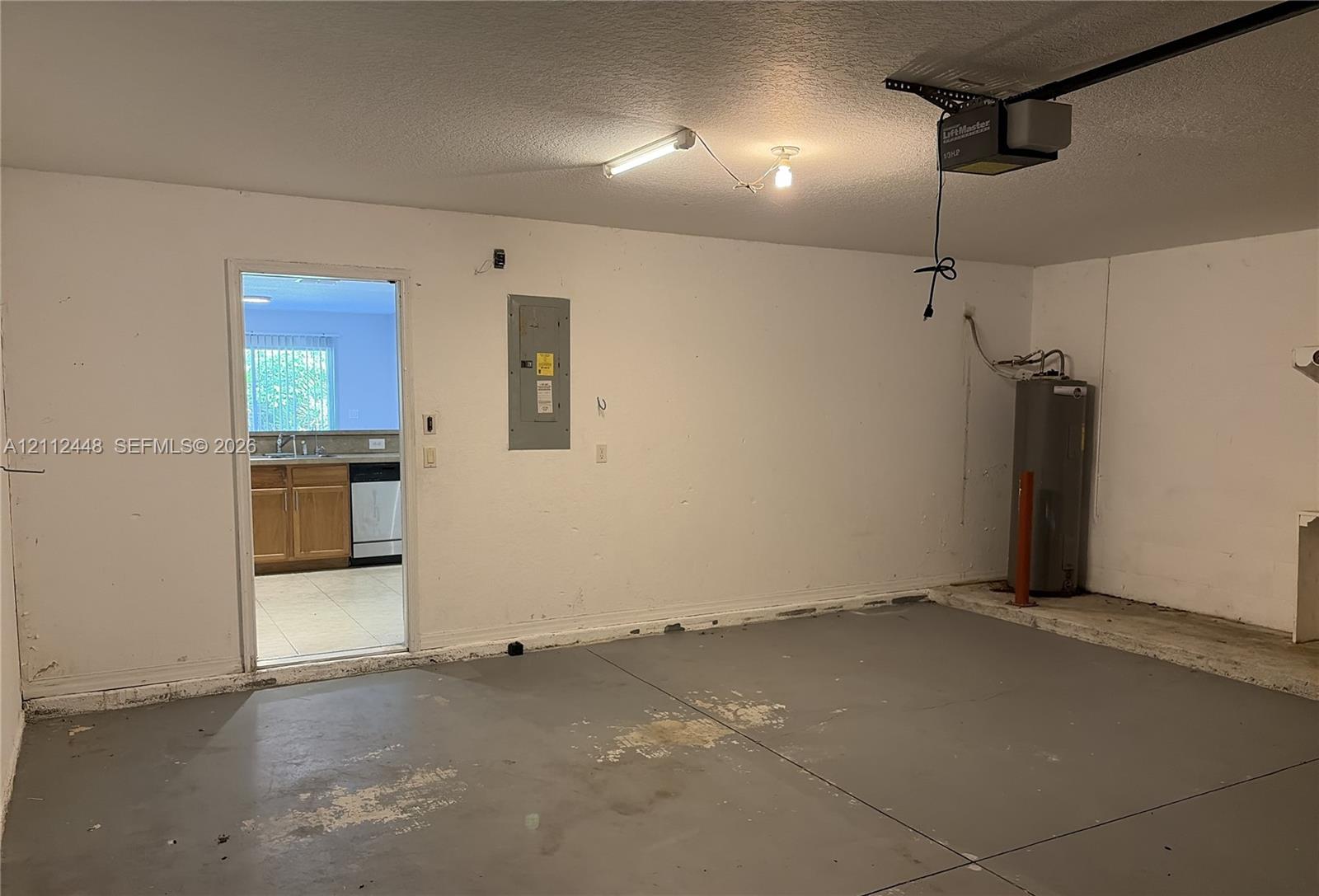 Enclosed garage space featuring a concrete floor, installed automatic door opener, and integrated water heater