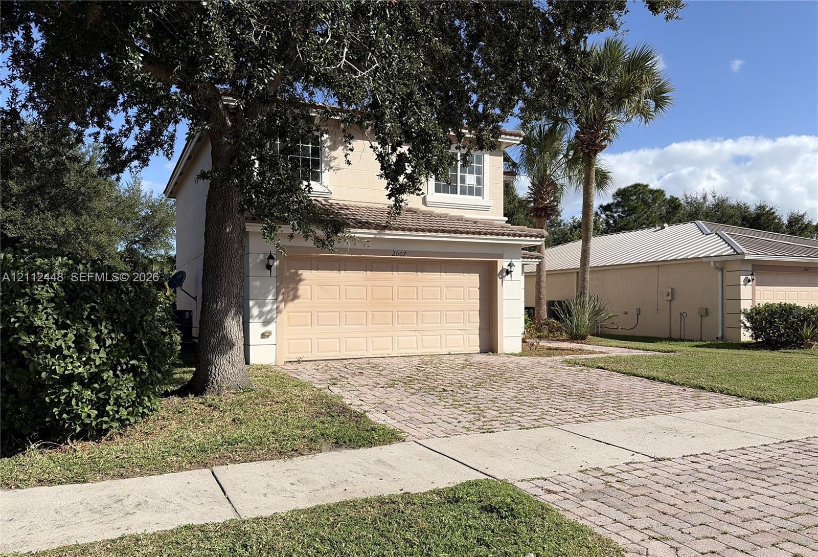 Two-story residence featuring a stucco exterior, concrete tile roof, attached two-car garage, and paver driveway
