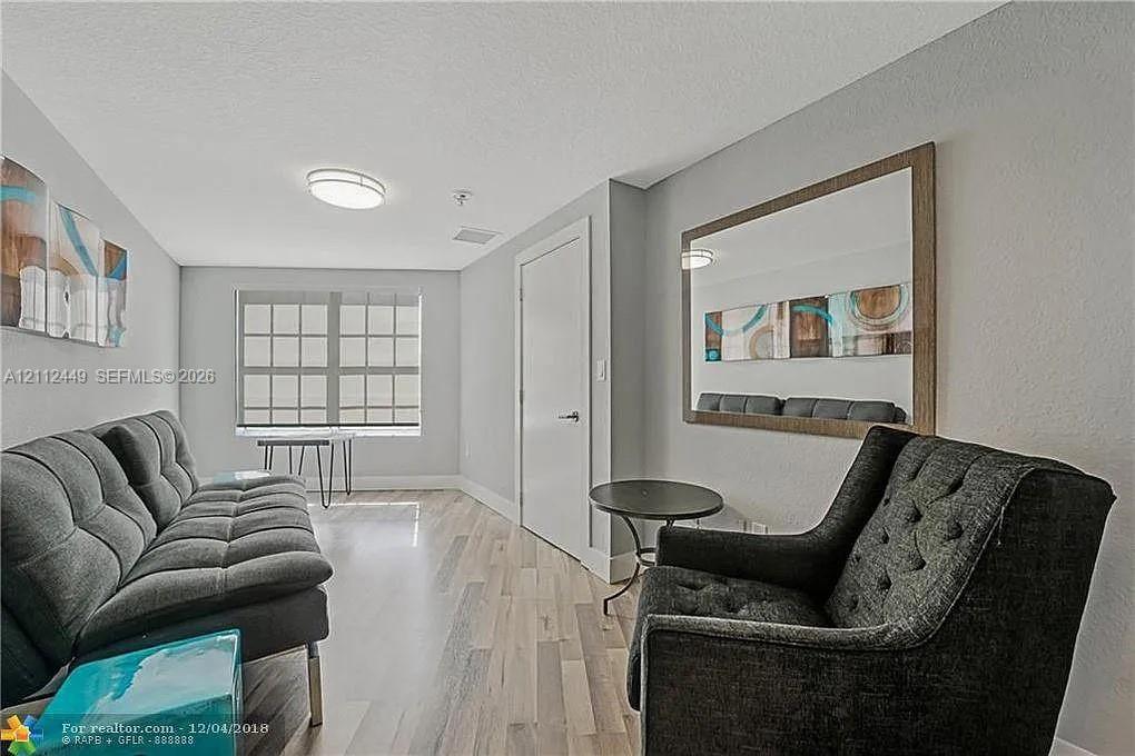 Wood-finish flooring, multi-pane window, flush-mount ceiling lighting, and wall-mounted mirror with a wood-tone frame