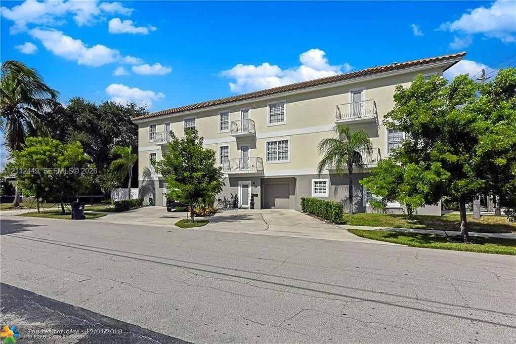 Multi-level exterior featuring a tile roof, stucco facade and private balconies.