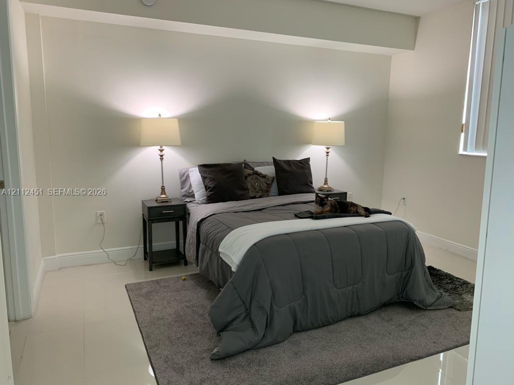 Neutral-toned room featuring smooth tile flooring, smooth-finish walls, and a recessed ceiling area