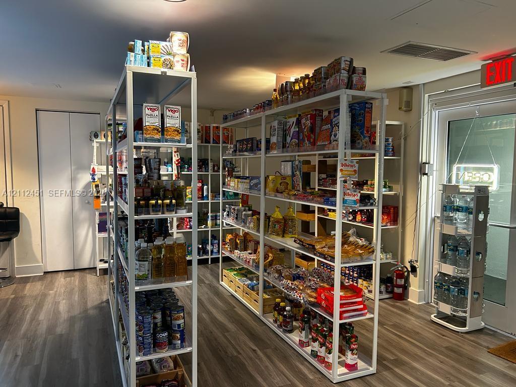 Storage room featuring wood-finish flooring, white metal shelving units, and a glass-paneled exterior door