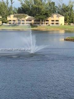 Waterfront setting featuring a central aerating fountain, expansive body of water, and surrounding grassy landscape Waterfront setting featuring a central aerating fountain, expansive body of water, and surrounding grassy landscape