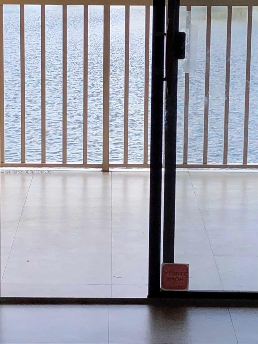 Balcony featuring light-toned tile flooring and metal railing, overlooking a body of water Balcony featuring light-toned tile flooring and metal railing, overlooking a body of water