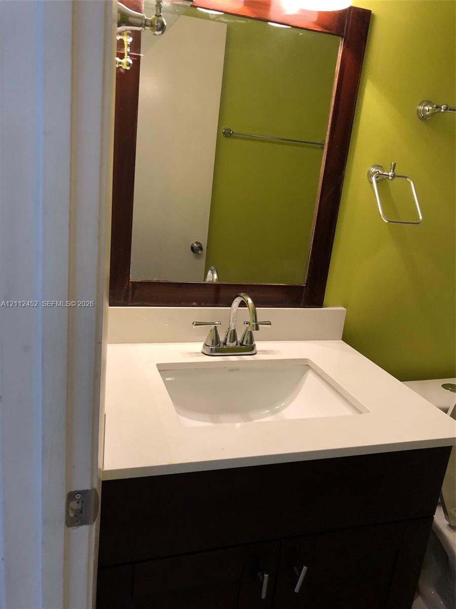 Dark wood-finish vanity with an integrated white sink, solid-surface countertop, dual-handle chrome faucet, and rectangular wood-framed wall mirror