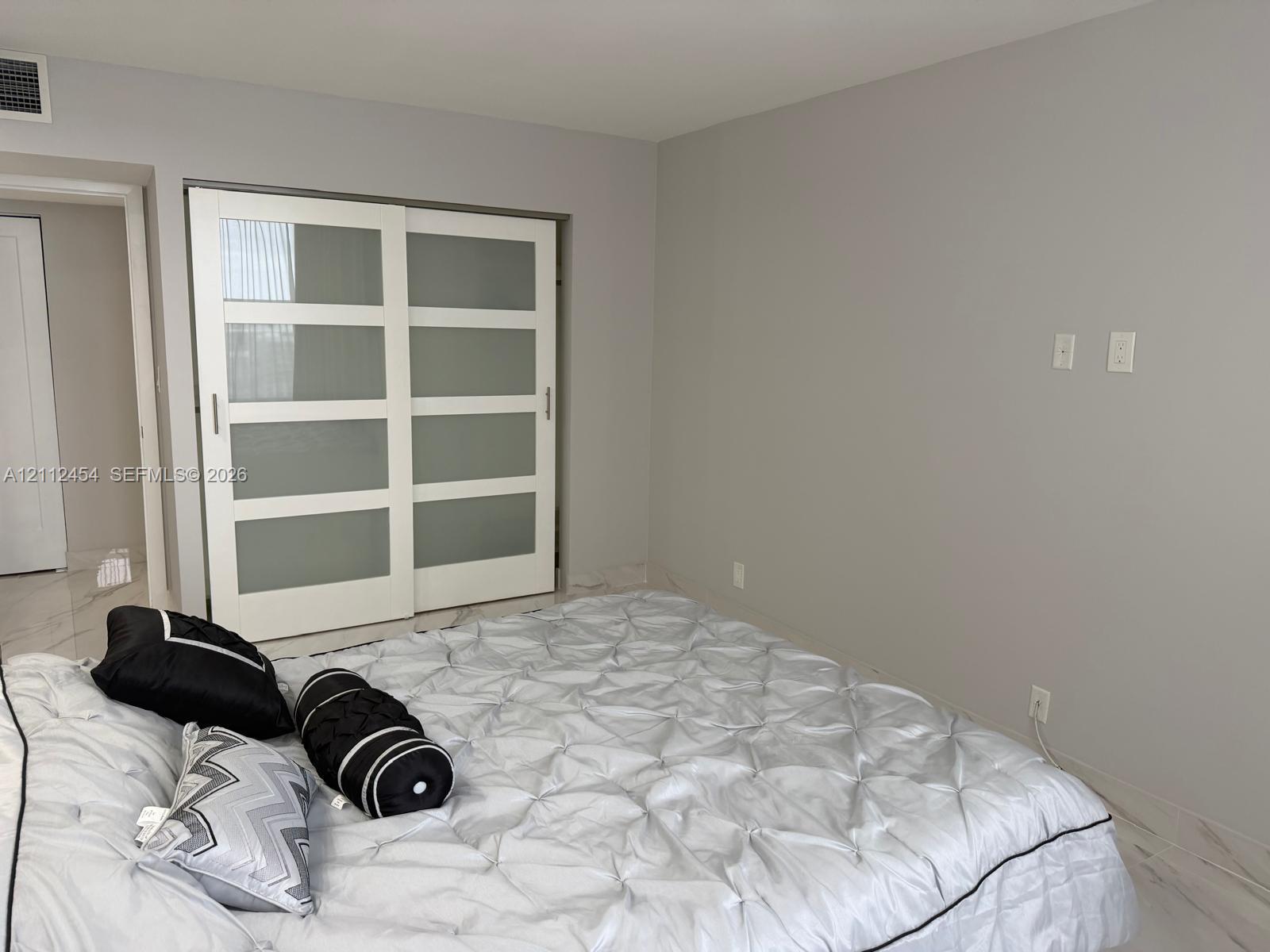 Sliding closet doors featuring frosted glass panels and white frames, stone-finish flooring, and neutral wall tones