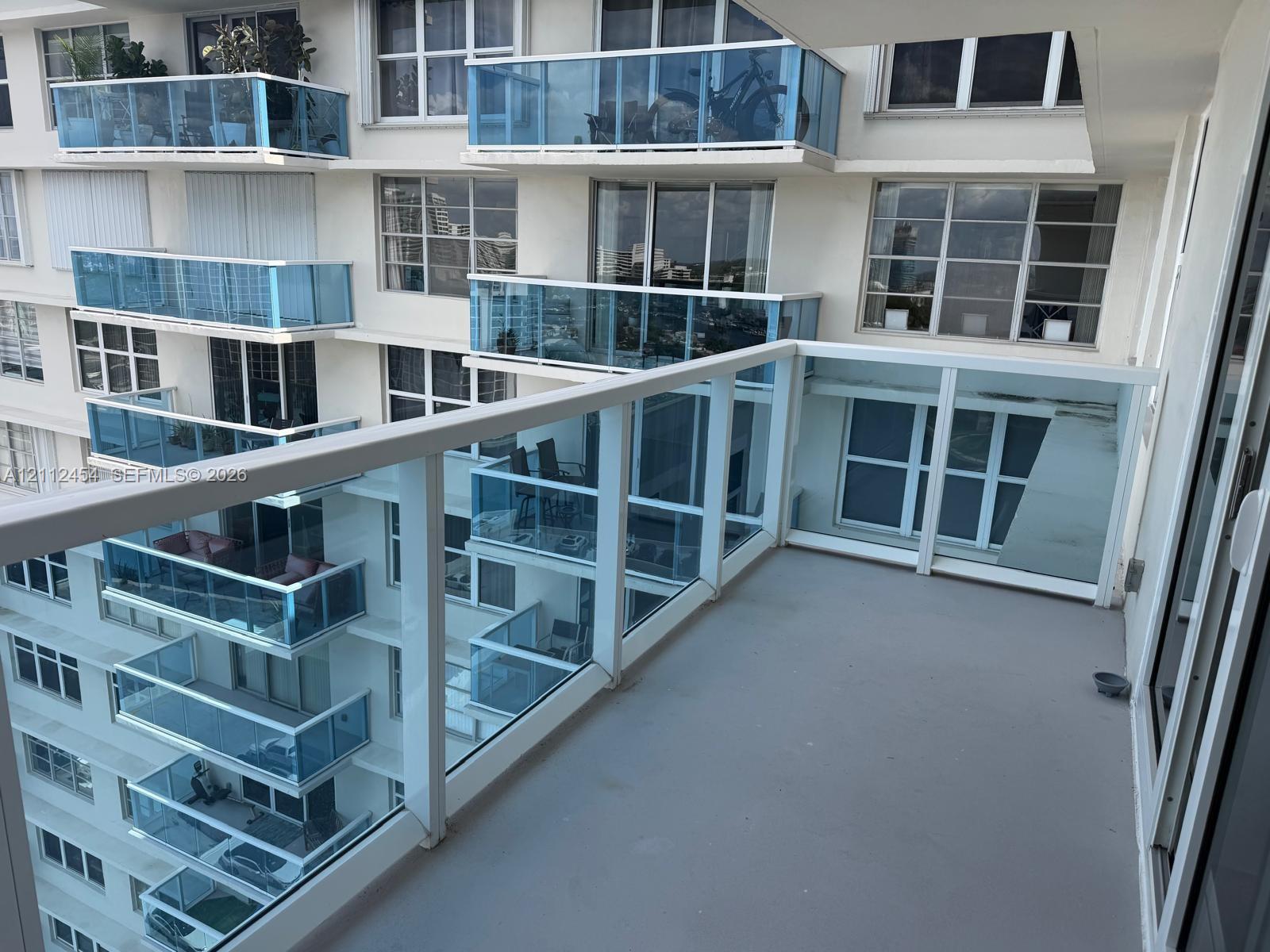 Private balcony featuring glass panel railings, a concrete floor surface, and large-format exterior window installations