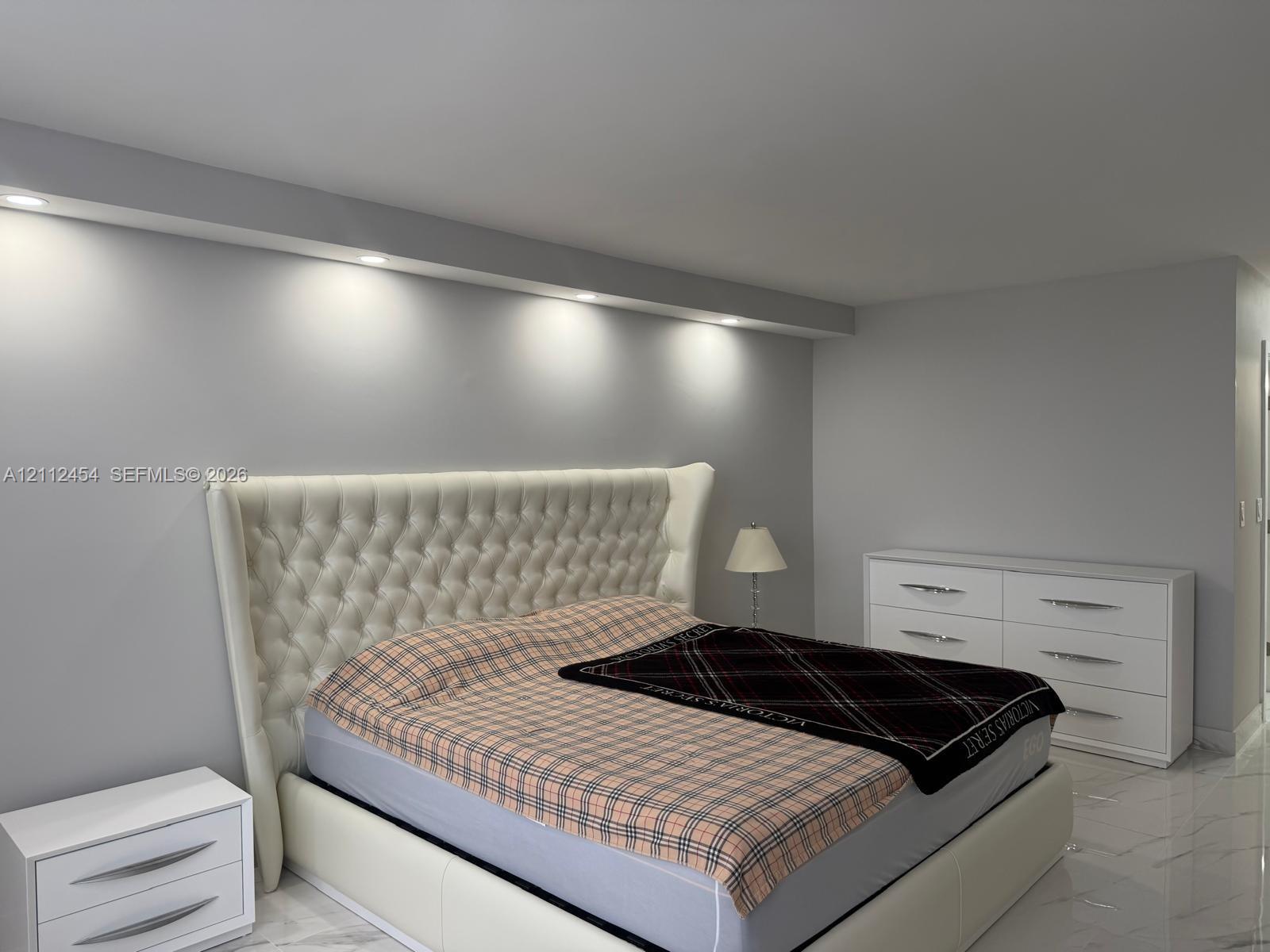 Neutral interior featuring light-toned flooring, recessed ceiling lighting, and a custom architectural soffit