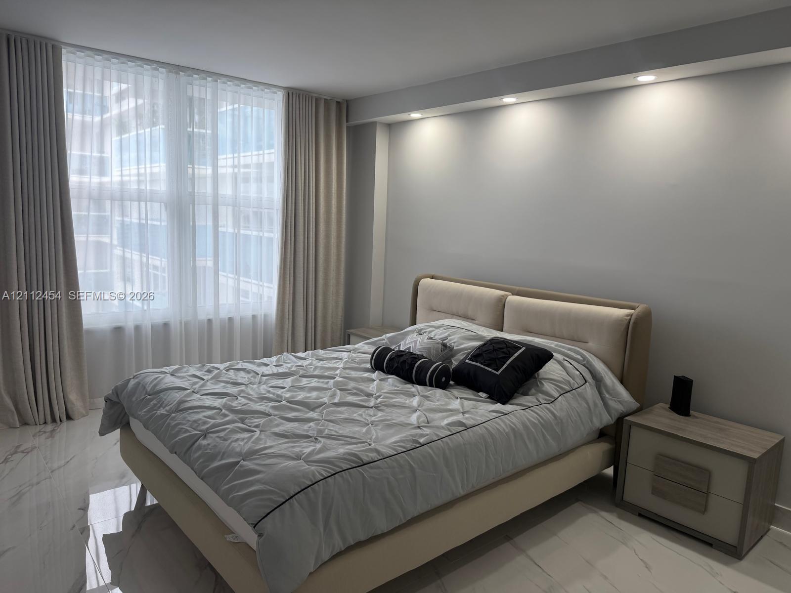 Floor-to-ceiling windows with floor-length drapery, recessed ceiling lighting, and polished stone-finish flooring