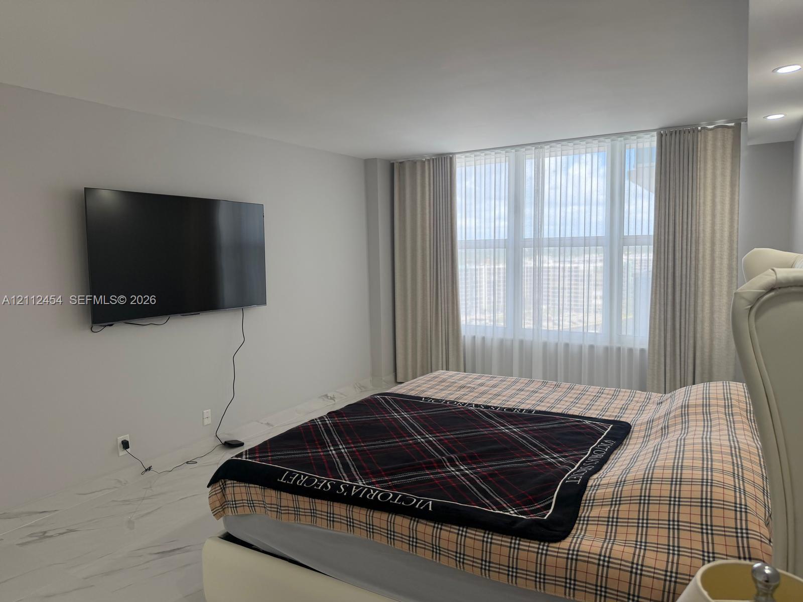 Spacious room featuring high-gloss large-format tile flooring, floor-to-ceiling windows with vertical blinds, and recessed lighting