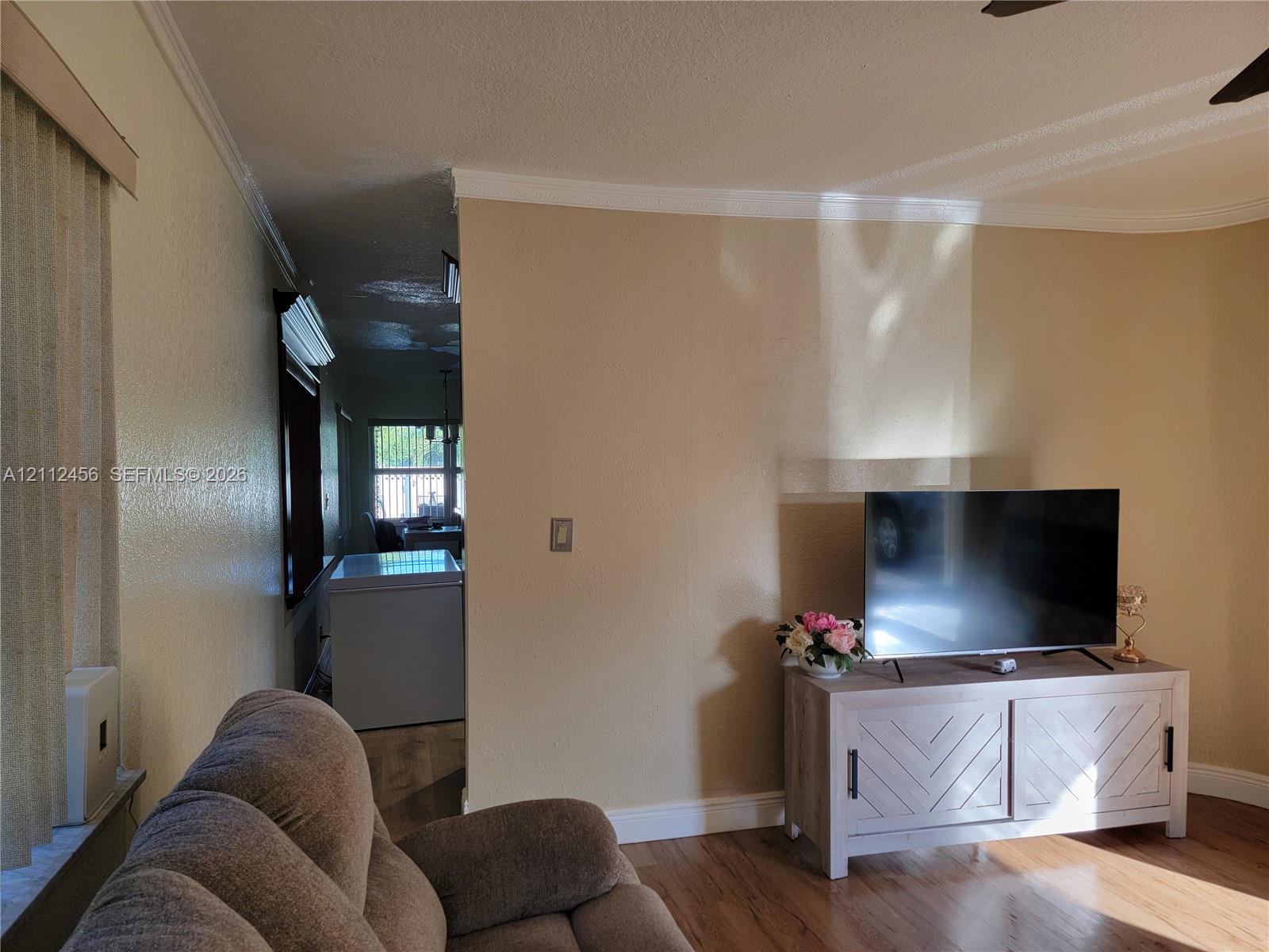 Wood-finish flooring, neutral wall tones, and crown molding