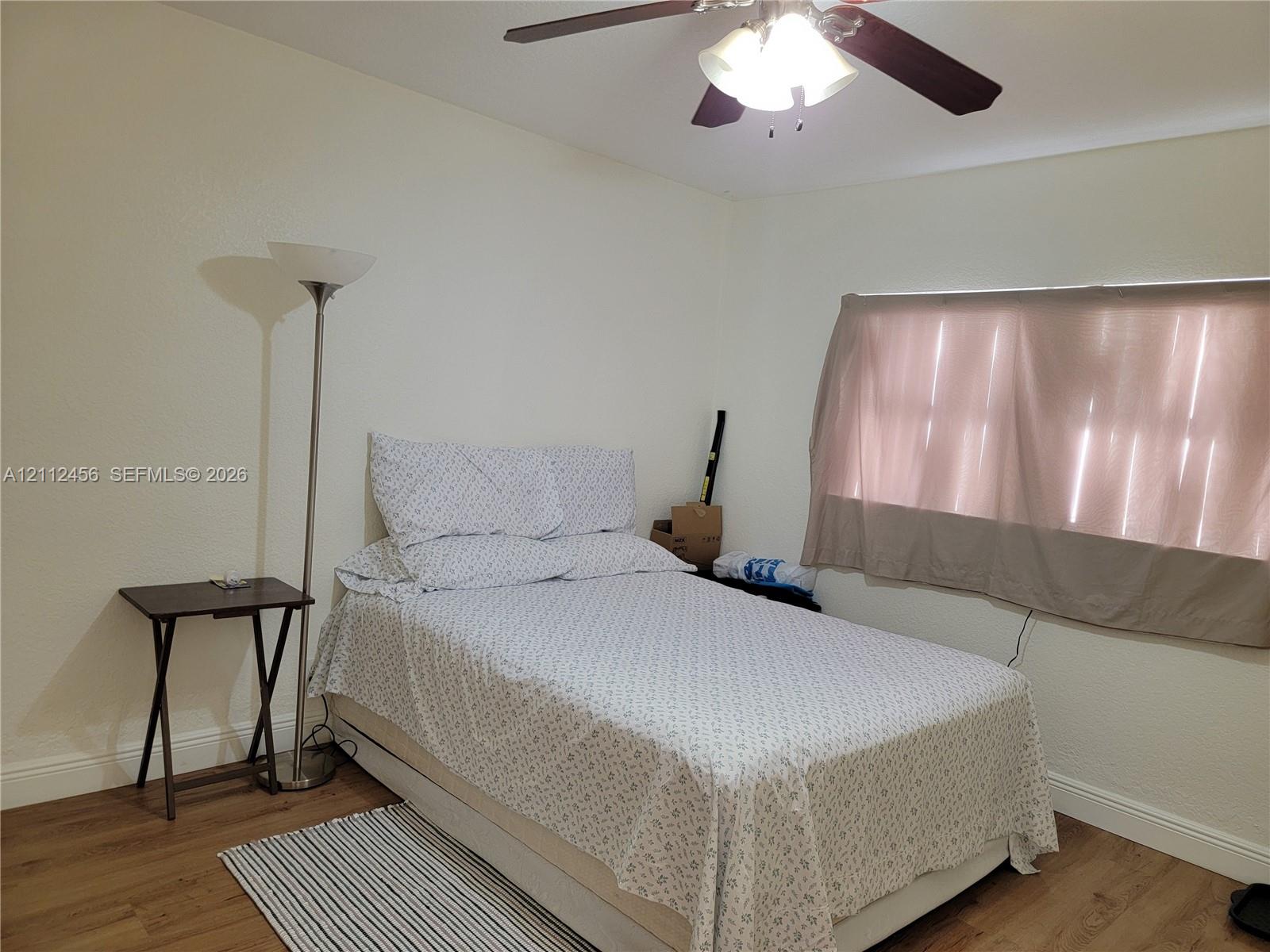 Room featuring wood-finish flooring and a ceiling fan with integrated light fixture