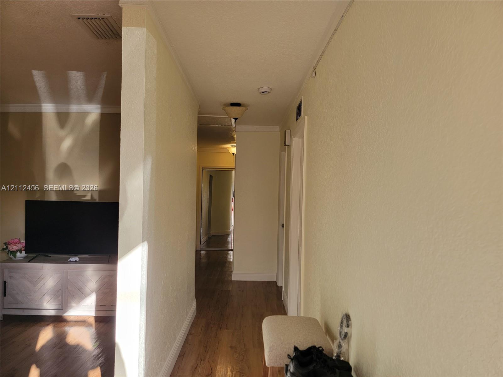 Interior hallway featuring wood-finish flooring, textured wall surfaces, and flush-mount ceiling lighting
