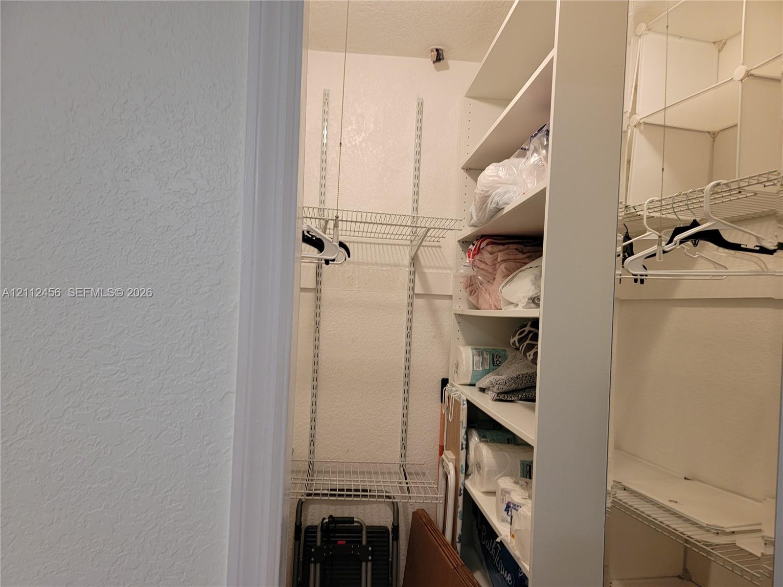 Walk-in storage space featuring built-in vertical shelving units and tiered wire rack organization systems