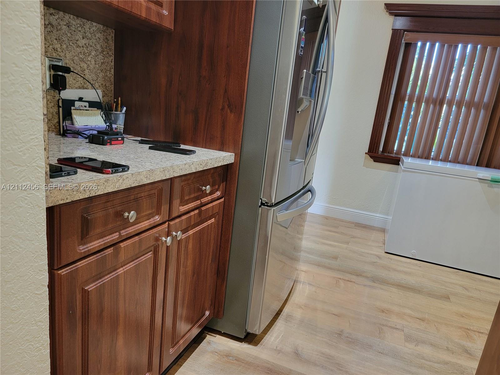 Wood-finish cabinetry with stone-patterned countertops, wood-finish flooring, and natural wood window casing