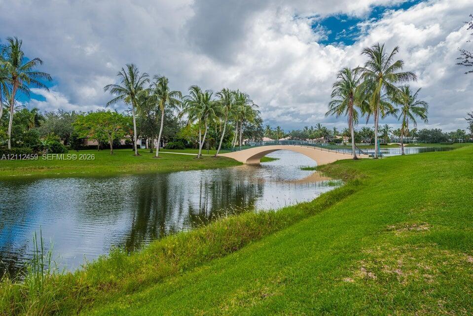 Manicured lawn, mature palm trees, arched pedestrian bridge, and waterfront setting