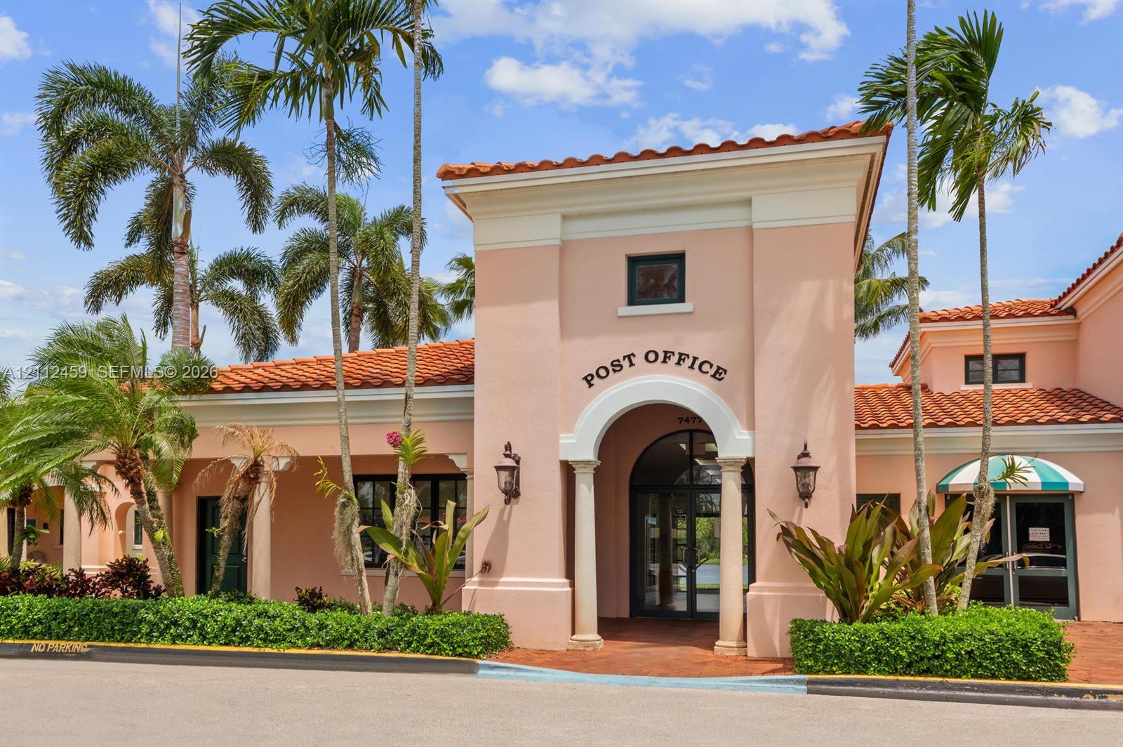 Stucco exterior with an arched entryway, terracotta tile roof, decorative columns, and landscaped perimeter