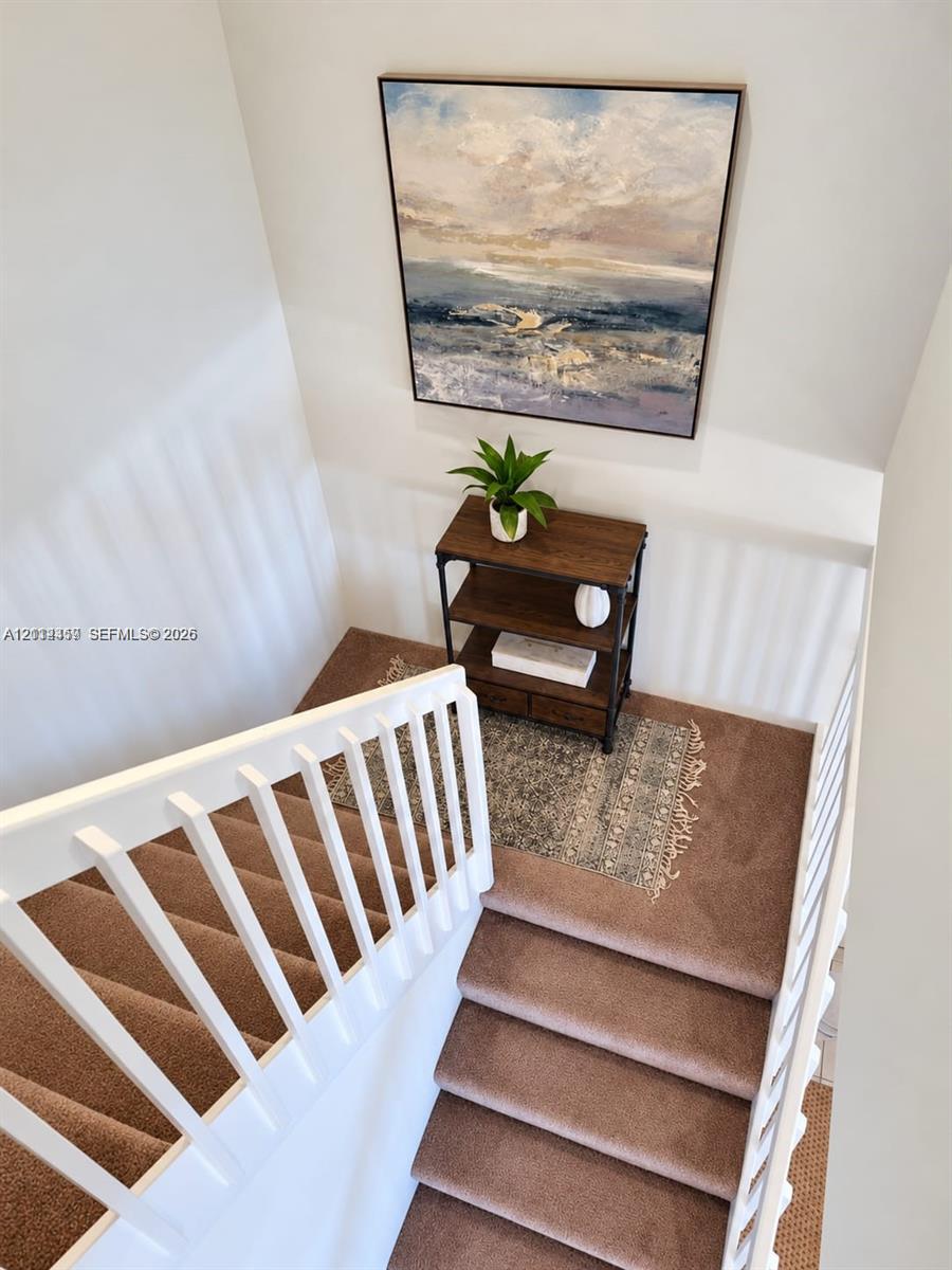 Staircase featuring wall-to-wall carpeting and a white wooden balustrade