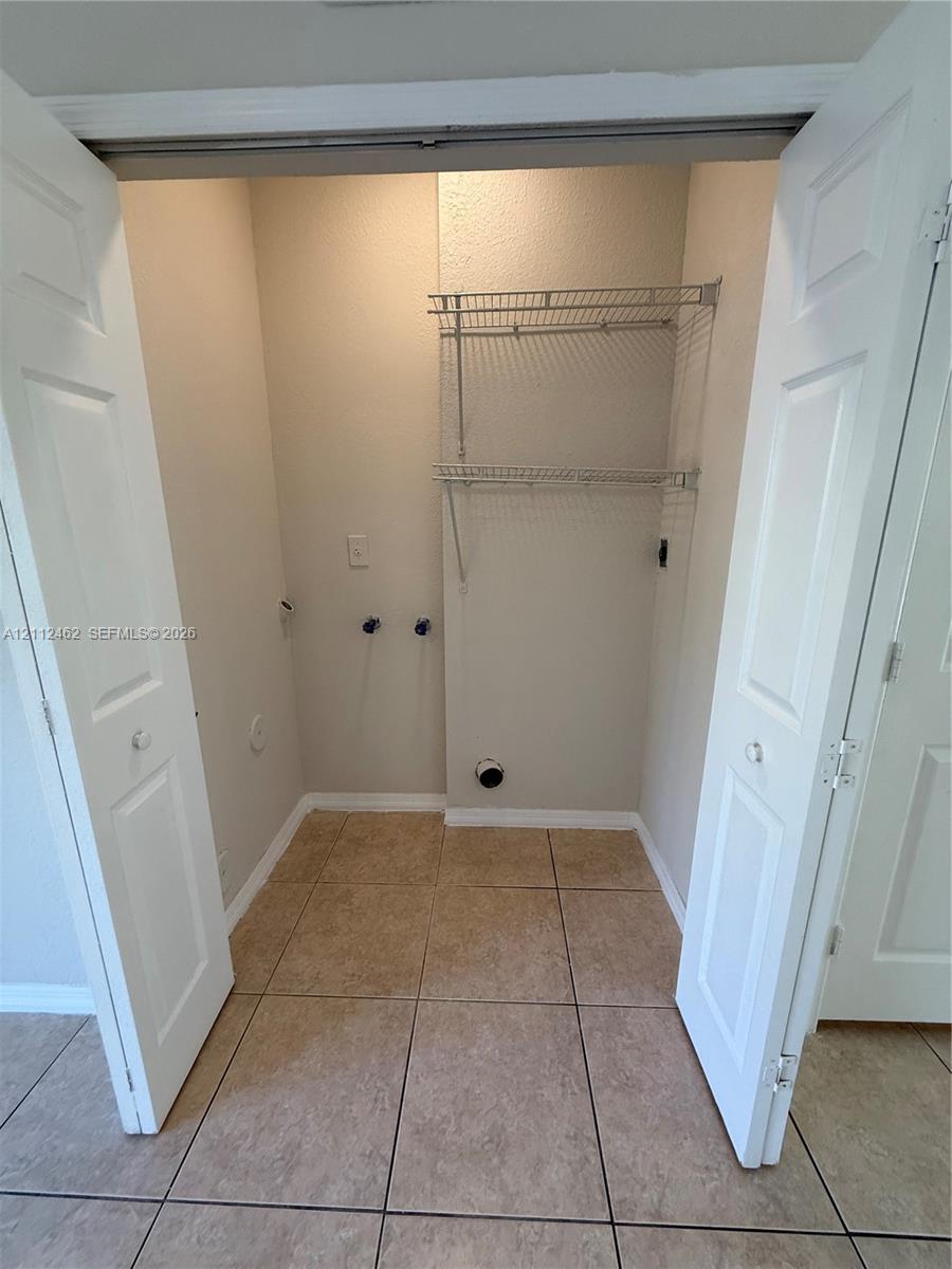 Utility closet featuring tile flooring, bi-fold doors, and integrated wire shelving
