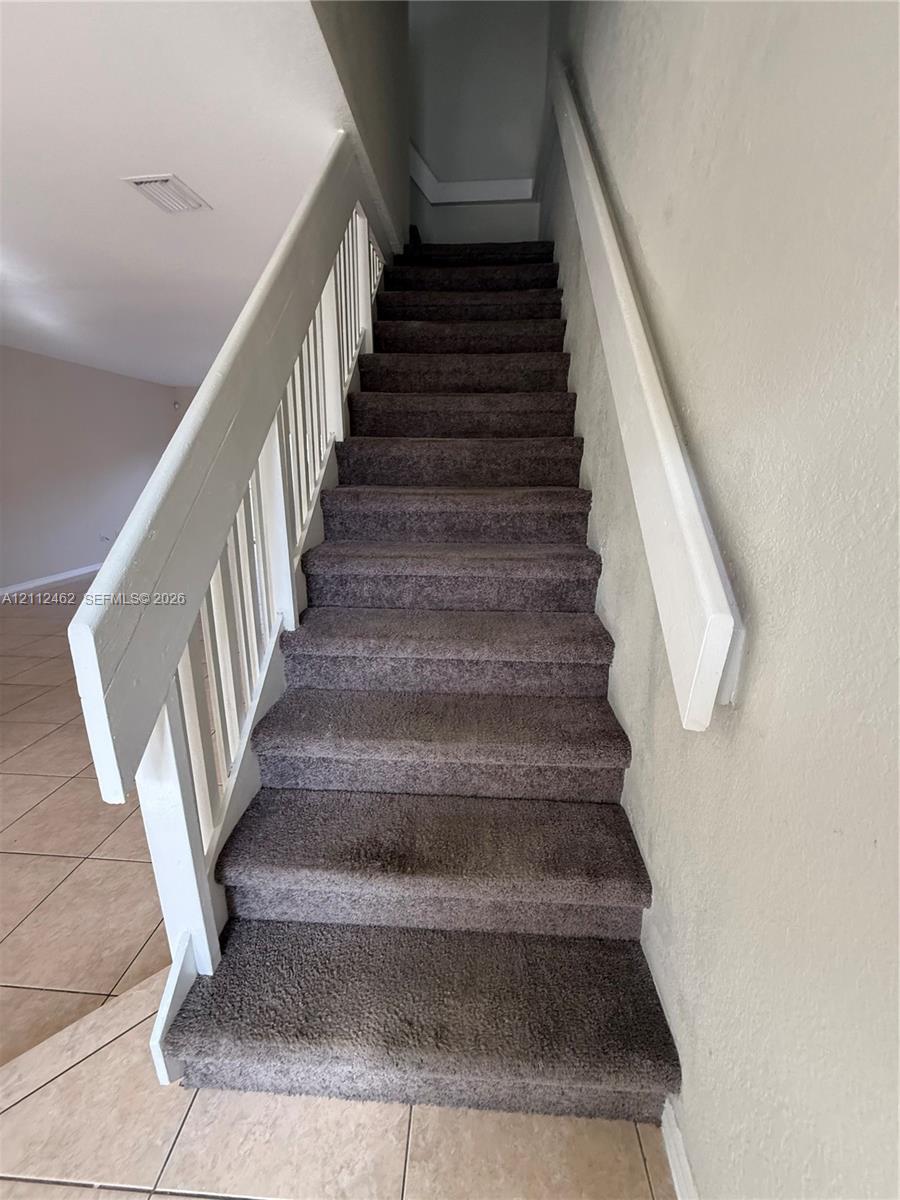 Staircase featuring wall-to-wall carpeting, a white wood railing, and a coordinating white handrail
