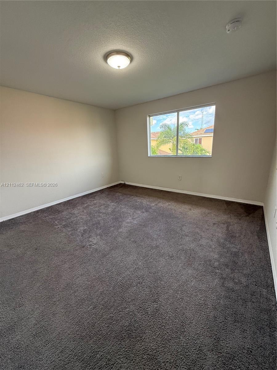 Neutral-toned interior space featuring wall-to-wall carpeting, a flush-mount ceiling light fixture, and a single-pane window