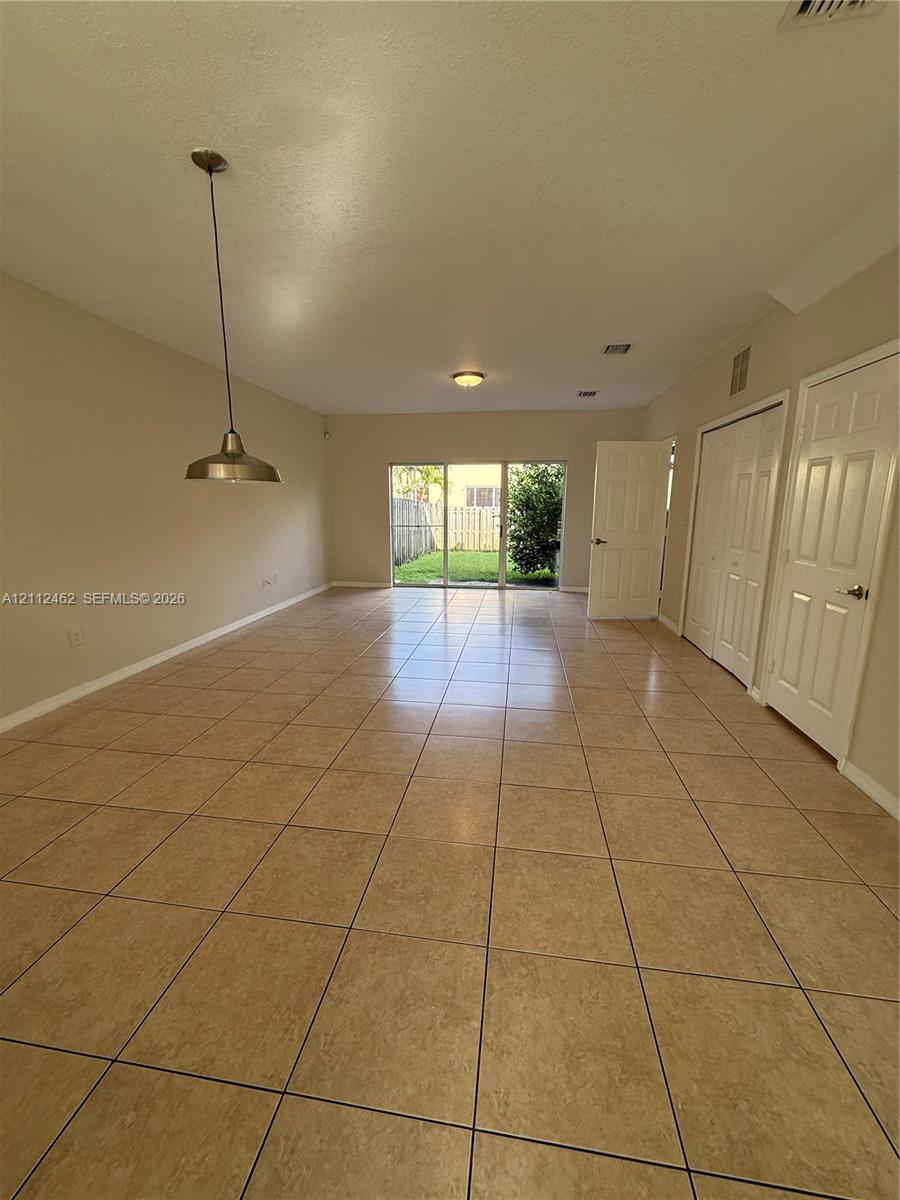 Interior space featuring neutral wall paint, large format ceramic tile flooring, a metal pendant light fixture, sliding glass doors, and interior paneled doors