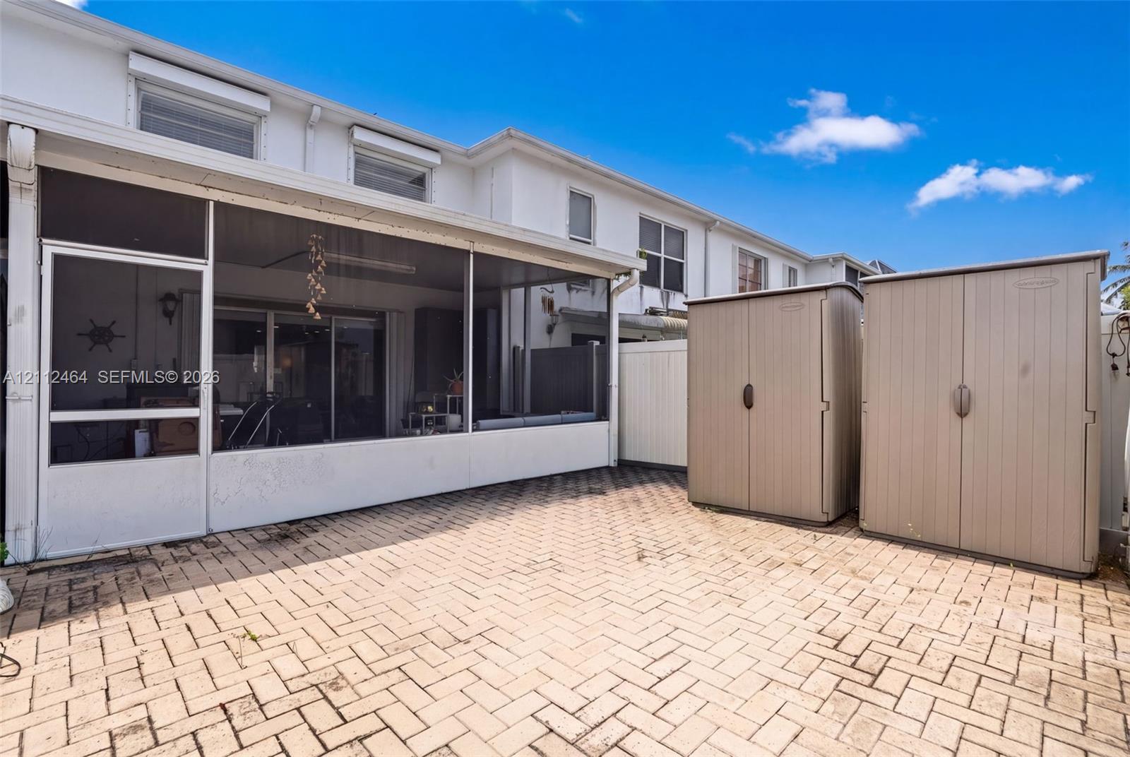 Screened-in patio with concrete paver flooring and white siding exterior